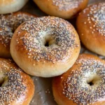 Freshly baked Sourdough Discard Bagels with sesame seeds on a wooden board, served with cream cheese and black coffee.