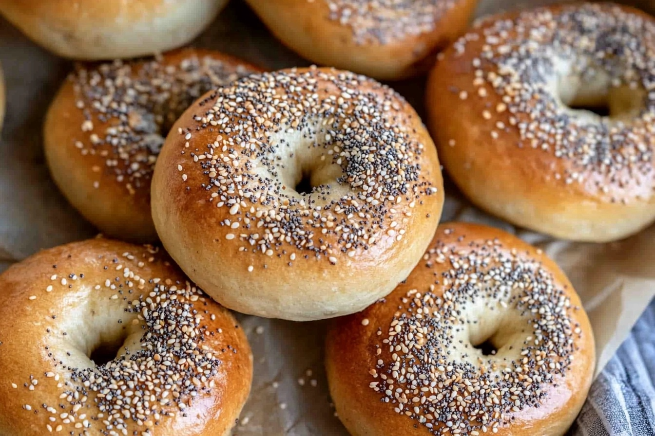 Freshly baked Sourdough Discard Bagels with sesame seeds on a wooden board, served with cream cheese and black coffee.