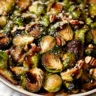 A plate of crispy, golden-brown LongHorn Steakhouse Brussels sprouts drizzled with a sweet and spicy glaze.