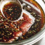 Raw steak in soy-based best japanese steak marinade with scallions and sesame in glass dish