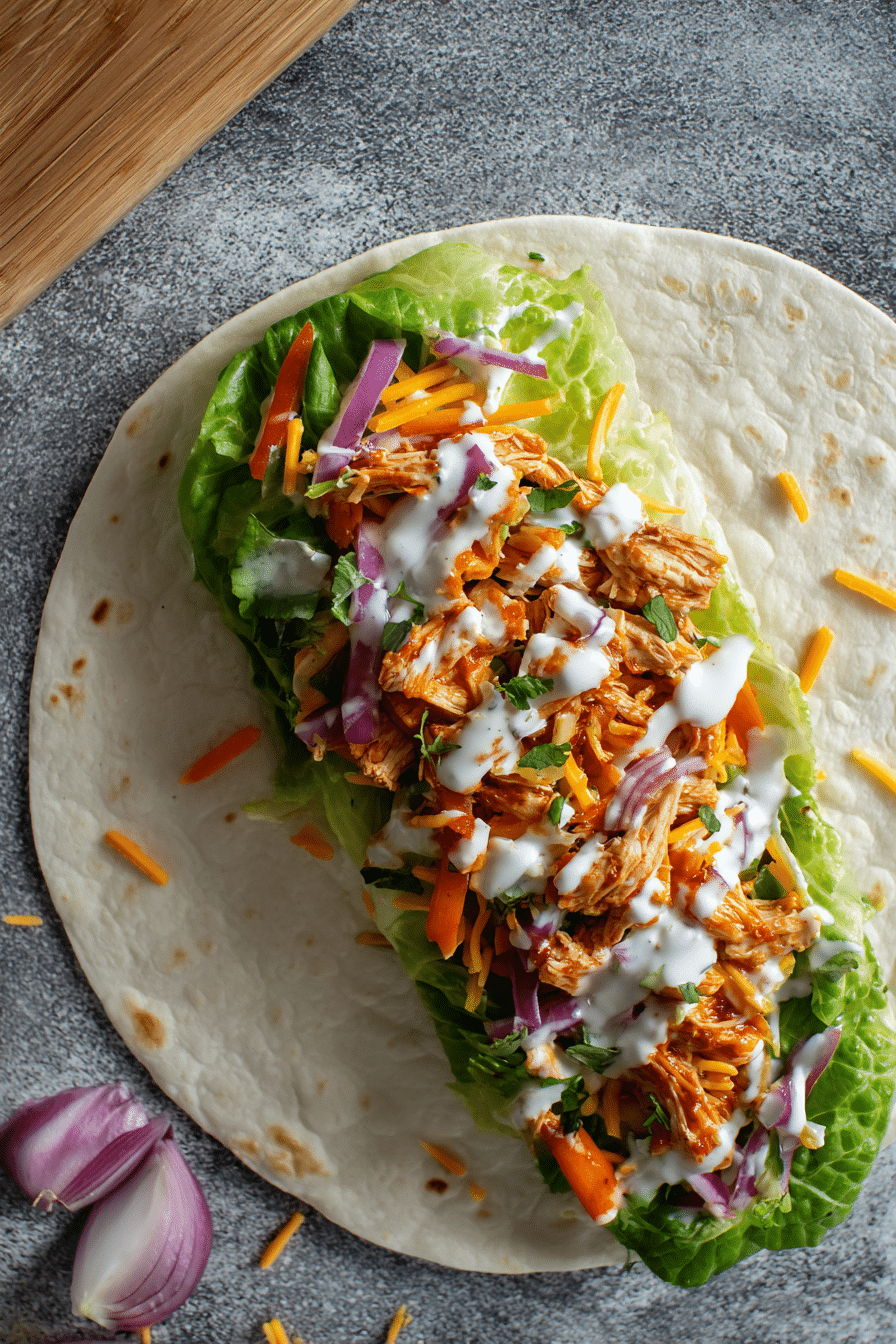 tortilla with layered lettuce, chicken, cheddar, ranch, and onions before rolling