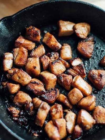 Hibachi chicken being glazed with soy sauce and melting butter in a hot skillet.