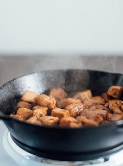 Hibachi chicken pieces searing in a cast iron skillet with visible browning.