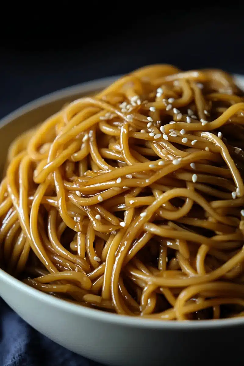 hibachi-noodles-cooking Hibachi noodles being stir-fried in a skillet with soy sauce and butter.