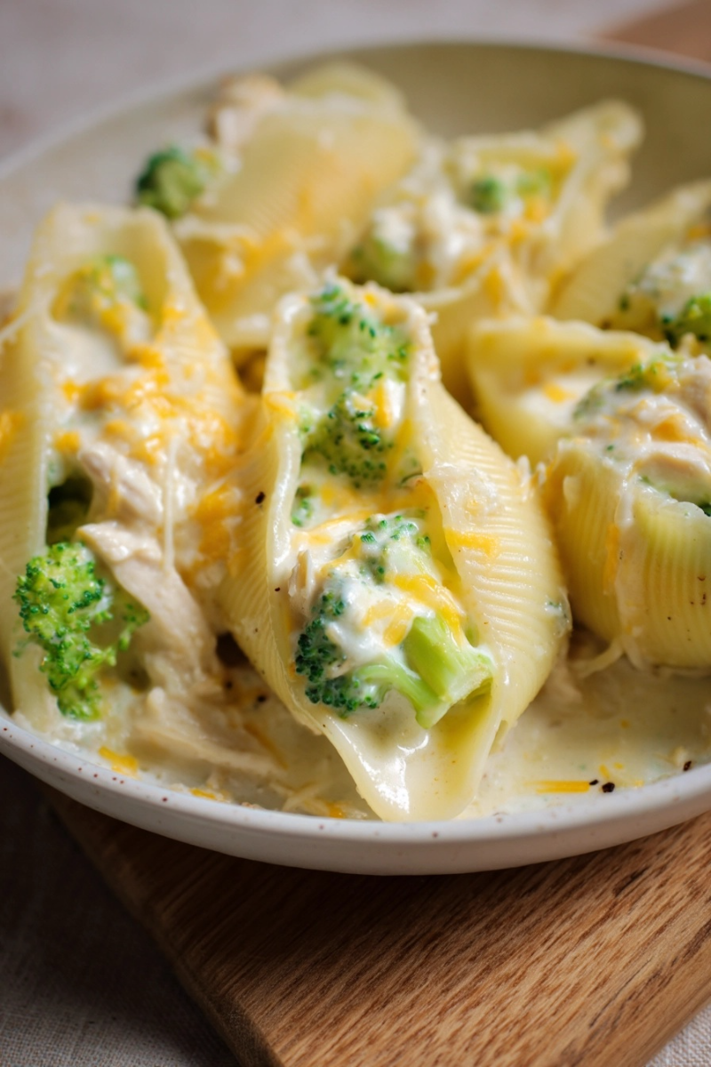ingredients-for-cheesy-chicken-and-broccoli-stuffed-shells Flat lay of ingredients for Cheesy Chicken & Broccoli Stuffed Shells including shredded chicken, broccoli, Alfredo sauce, cheeses, and jumbo pasta shells.