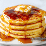 Woman flipping cornmeal flapjacks on a cast iron skillet