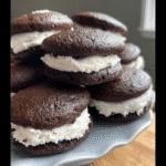 Experience the authentic charm of homemade sourdough whoopie pies. This image captures two rustic whoopie pies resting on a piece of parchment paper next to a jar of sourdough starter.